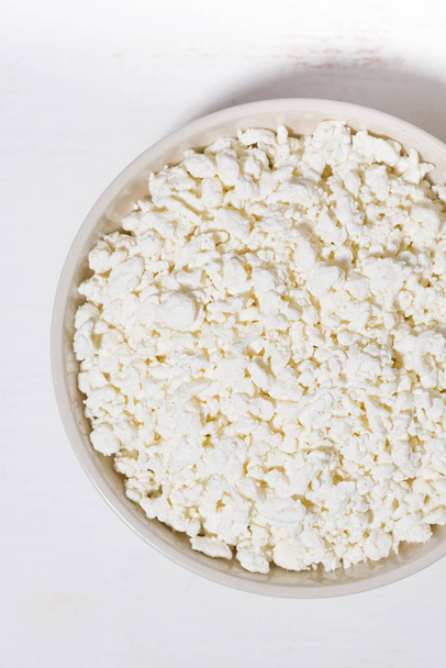 bowl of fresh farm cottage cheese on a white background, closeup - Фото, зображення
