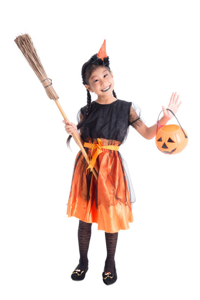 Volledige lengte van Aziatische meisje in heks kostuum staande en holding Halloween pompoen emmer over witte achtergrond - Foto, afbeelding