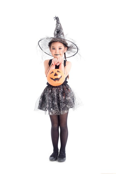 longitud completa de poco asiático chica en bruja traje de pie y celebración halloween calabaza cubo sobre blanco fondo
 - Foto, Imagen