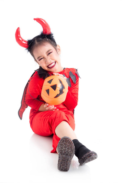 Lunghezza completa della bambina in costume rosso diavolo seduta e sorride
 - Foto, immagini
