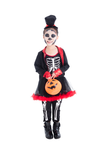 Comprimento total de menina em traje de esqueleto segurando halloween balde de abóbora, de pé e sorri
  - Foto, Imagem