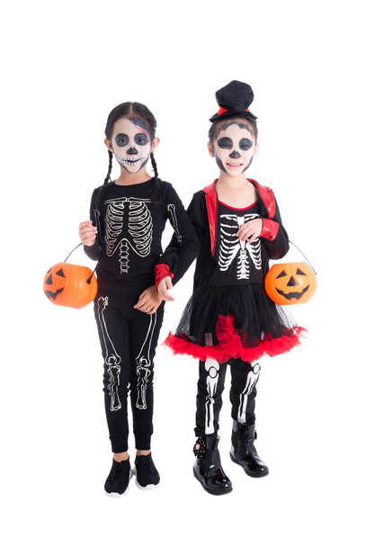 Two asian girls in skeleton costume holding halloween pumpkin bucket and smiles - Photo, Image
