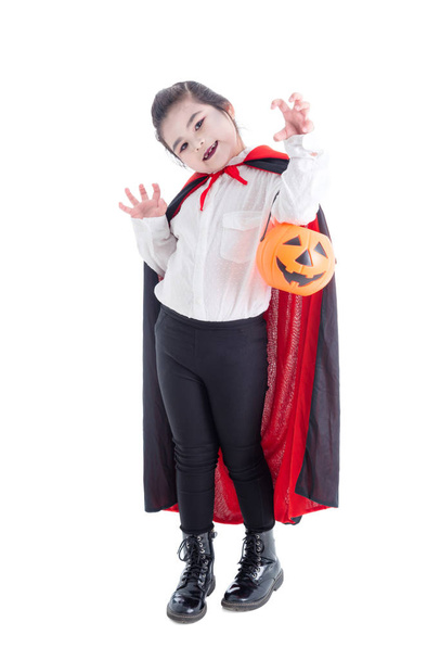 Full length of girl in vampire costume holding halloween pumpkin bucket and smiles  - Photo, Image