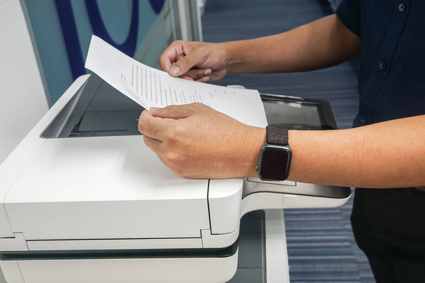 primer plano hombre de negocios sostiene hoja de papel blanco para copia y escaneo en la impresora de oficina moderna
 - Foto, imagen