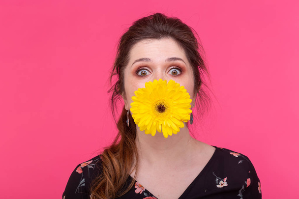 Summer, flowers, funny and people concept - woman having fun with gerberas over the pink background - Photo, Image