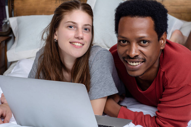 Jeune couple utilisant un ordinateur portable dans un lit à la maison
. - Photo, image