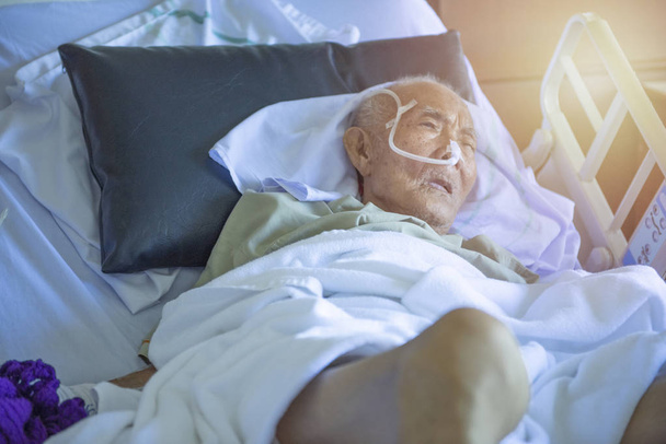Azjatycki starszy mężczyzna chory i ma rurkę w oddziale szpitalnym, spać w śpiączce stan na łóżku - Zdjęcie, obraz