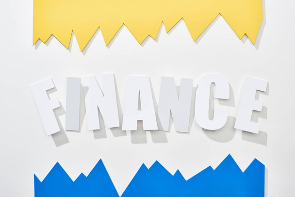 top view of finance inscription with blue and yellow statistic graphs on white background - Foto, imagen