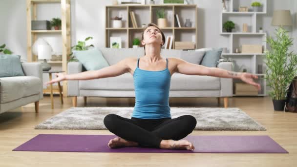 Pretty woman in lotus position doing namaste in living room - Footage, Video