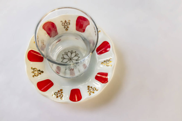 Nahaufnahme traditioneller türkischer Teeglasbecher und kleiner gemusterter Teller auf weißem Hintergrund. - Foto, Bild