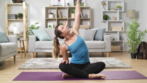 Csinos nő a Sportruházat ül a padlón otthon és stretching gerinc - Felvétel, videó