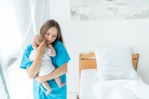 attractive and young mother holding her child in hospital  - Photo, image