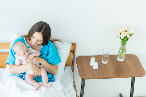 hastanede çocuğunu tutan çekici ve genç anne  - Fotoğraf, Görsel