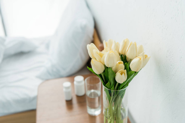 foco selectivo de tulipanes con hojas en mesa de madera en la clínica
  - Foto, Imagen