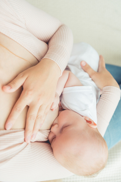 cropped view of mother breastfeeding her child in apartment  - 写真・画像