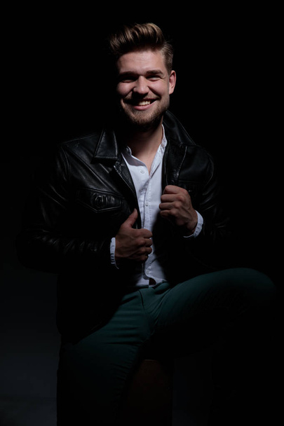 homem casual feliz segurando colar de jaqueta de couro está rindo
 - Foto, Imagem