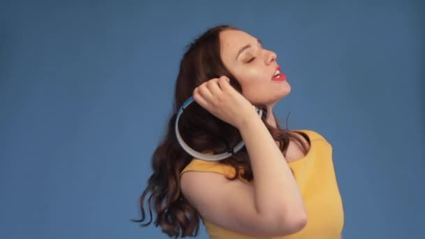 Young girl in yellow shirt and headphones listening music - Metraje, vídeo
