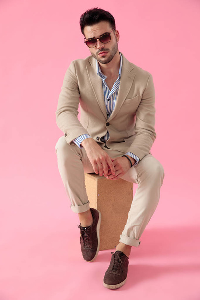 smart casual man wearing a suit seated on a wooden box - Photo, Image
