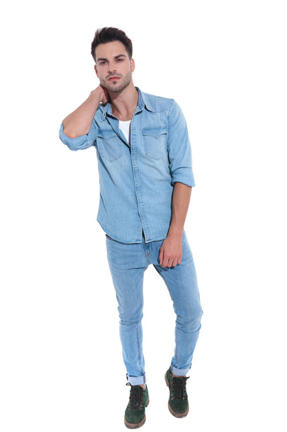 confident man dressed in denim posing with hand behind neck - Foto, immagini