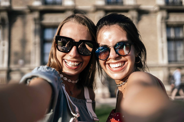 Happy young women in sunglasses taking selfie - 写真・画像