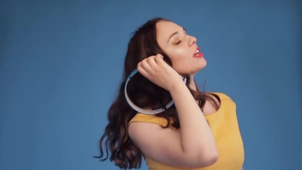 Jovial young woman dancing while listening to music in headphones. - Materiaali, video