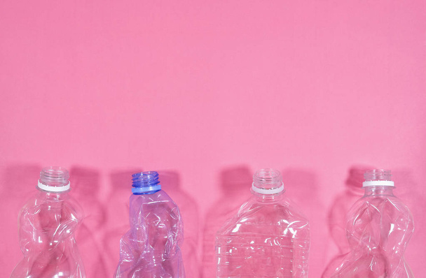 Пластиковые бутылки изолированы на розовом фоне. Концепция утилизации отходов. Пластиковые домашние питомцы
. - Фото, изображение