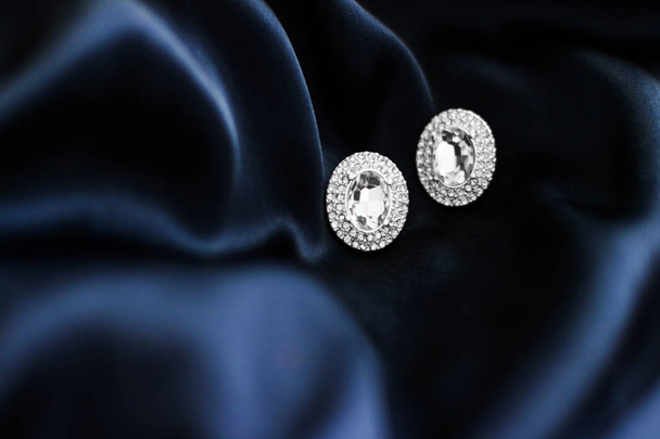 Розкішні діамантові сережки на темно-синьому шовковому фоні, святковий глем
 - Фото, зображення