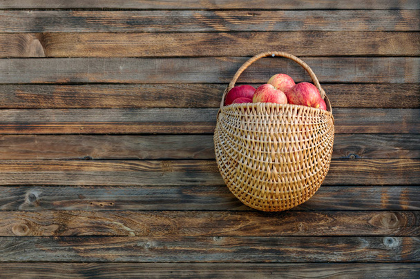 Korb mit Äpfeln auf einem Holzzaun.  - Foto, Bild
