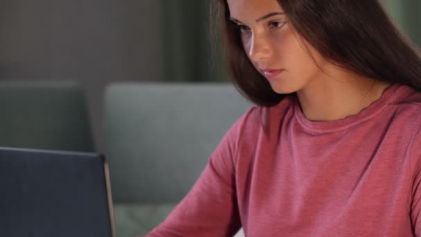 smiling brunette in purple sweatshirt looks at modern laptop - Video, Çekim
