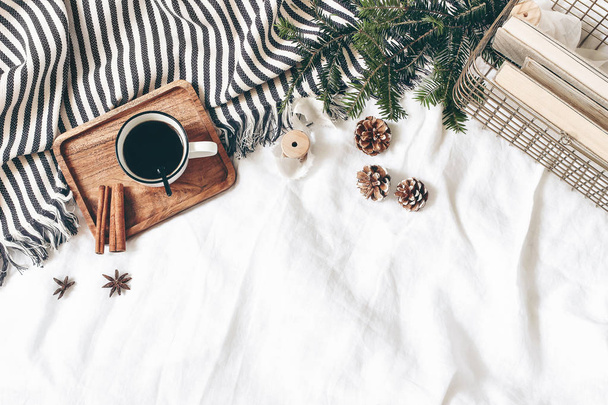 Christmas styled composition. Cup of coffee, plaid, old books in golden basket, pine cones, fir branches on white table, linen background. Flat lay, top view. Winter holiday lifestyle concept, web - Fotoğraf, Görsel