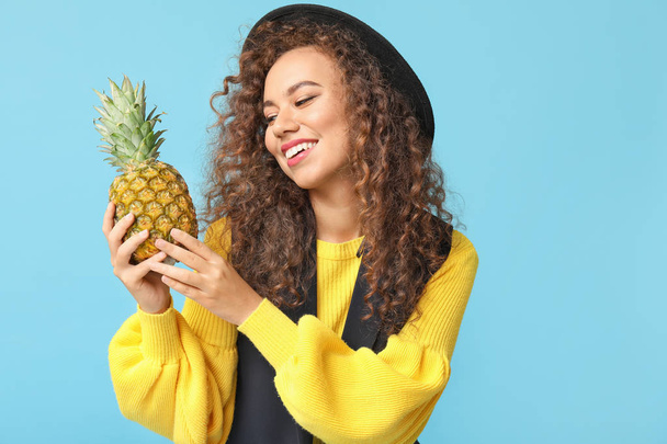 Stylish African-American woman with pineapple on color background - Foto, Bild