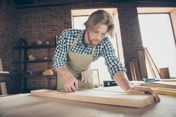 Low angle view of his he nice attractive handsome blond concentrated focused guy measuring board studio shop owner at industrial brick loft style interior indoors workplace - Photo, image