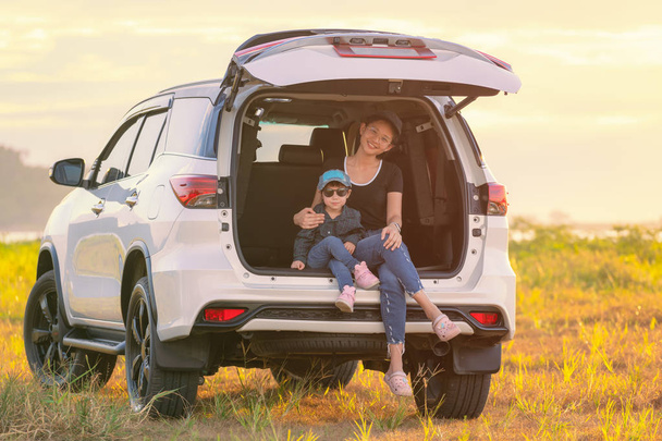 Молодая мать с симпатичной дочерью, сидящей сзади автомобиля
  - Фото, изображение