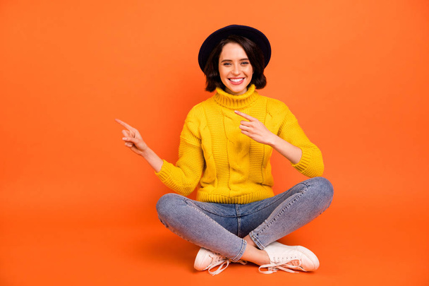 Photo of charming nice cute cheerful girl pointing at space to be filled up adverting something while isolated with orange background - Foto, Bild