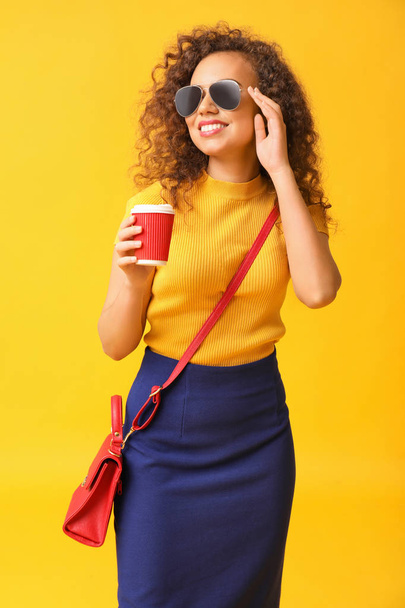 Stílusos afro-amerikai nő csésze kávé színes háttér - Fotó, kép