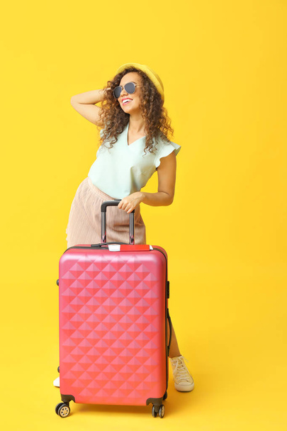Stylish African-American woman with luggage on color background - 写真・画像
