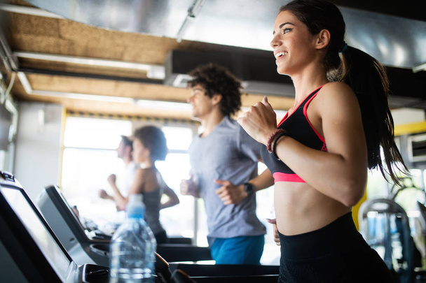 Fit happy people running in machine treadmill at fitness gym - Foto, Imagen