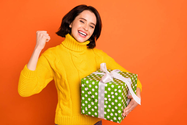 Photo of cheerful celebrating girl rejoicing with having received gift and fun from someone close while isolated with orange background - Foto, imagen