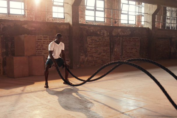 Fitness workout. Sport man doing battle rope exercise at gym - Photo, image