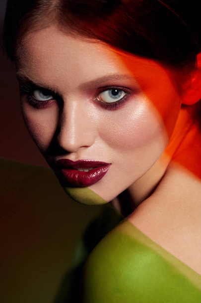 Schoonheid make-up. Vrouw model gezicht met rode lippenstift in kleur licht - Foto, afbeelding