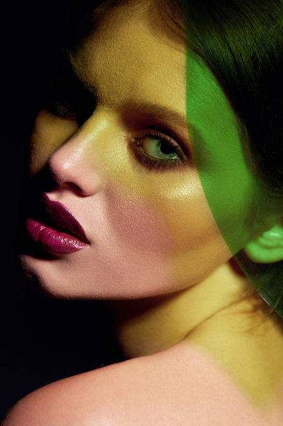 Fashion model with beauty face makeup under green neon color - Foto, afbeelding