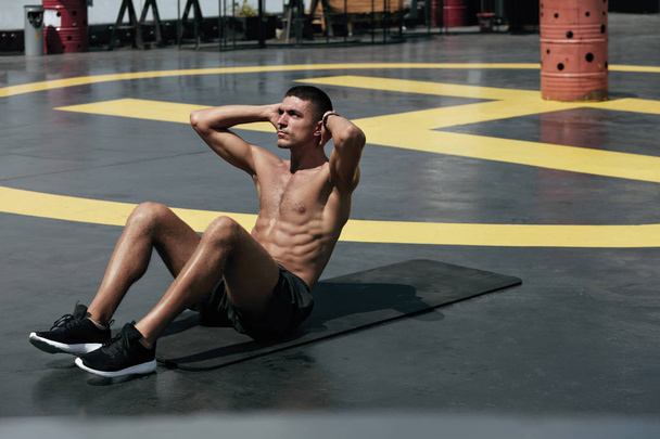 Homem do esporte fazendo abdominais crunches exercício, treino de fitness na rua
 - Foto, Imagem