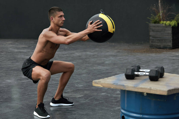 Exercise. Sport man doing squat workout with med ball at gym - Foto, Imagem