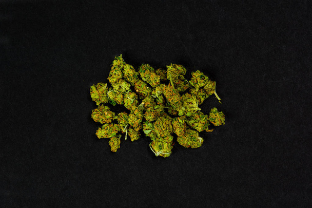 Снимок с воздуха нескольких бутонов марихуаны на черном фоне. Цветок женского растения конопли
 - Фото, изображение