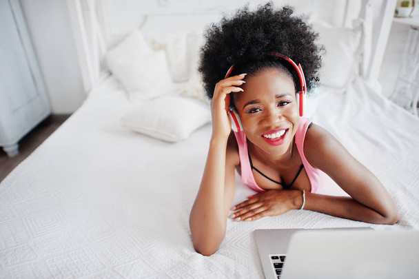Young african american woman lying on the bed while working on l - Foto, Imagem
