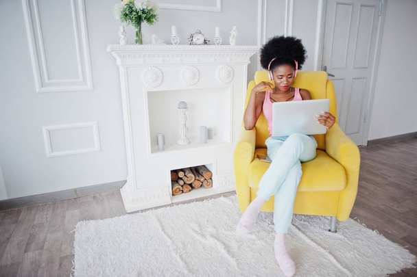 Young african american woman sitting in yellow chair while worki - Foto, imagen