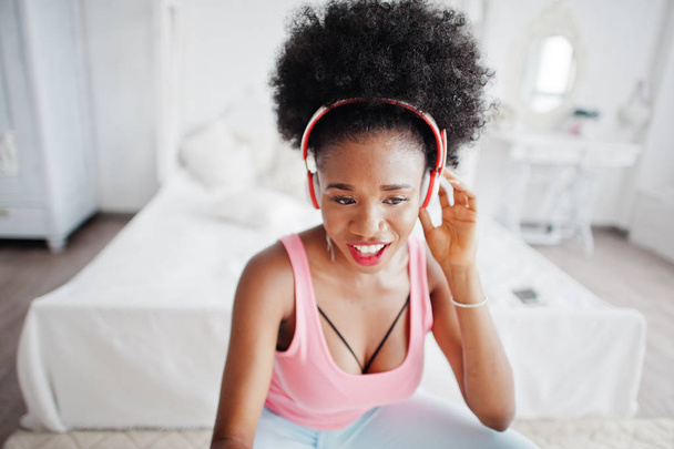Young african american woman in pink singlet listen music on ear - 写真・画像