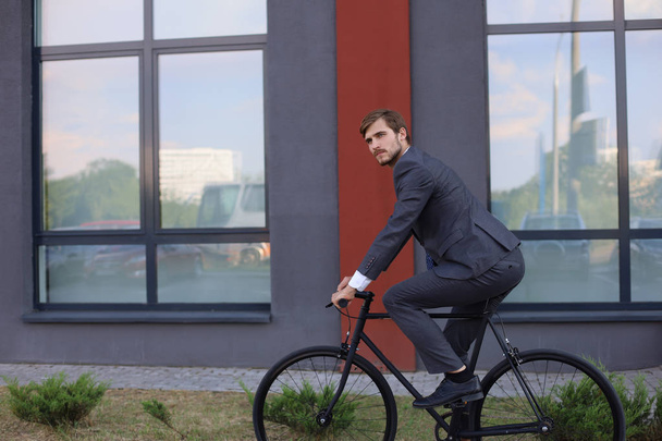 Handsome young businessman riding on his bicycle in the city. Ecologic transport concept.  - Photo, Image