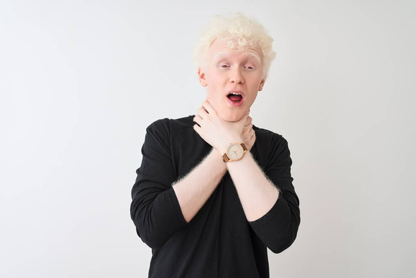 junger Albino-blonder Mann in schwarzem T-Shirt, der vor isoliertem weißen Hintergrund steht und schreit und erstickt, weil er qualvoll erwürgt wird. Gesundheitsprobleme. Erstickungs- und Selbstmordkonzept. - Foto, Bild