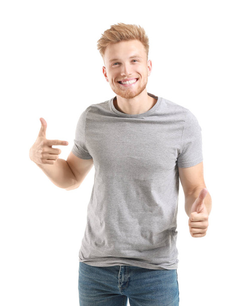 Homem apontando para sua camiseta e mostrando polegar para cima contra fundo branco
 - Foto, Imagem